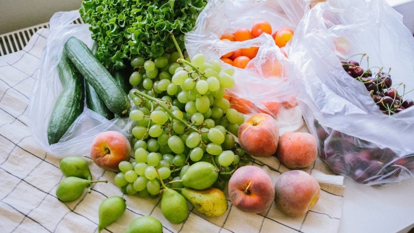 A colorful display of fresh fruits and vegetables on a table with plastic bags.