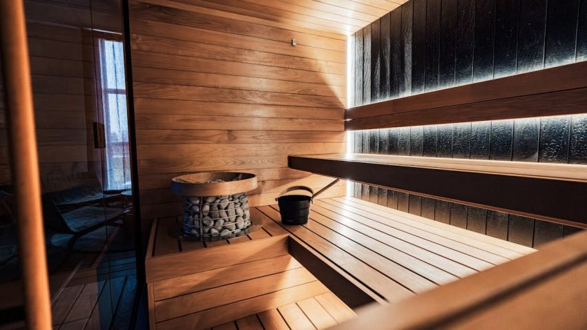 Elegant indoor sauna featuring wooden panels, sauna heater, and a tranquil ambiance.